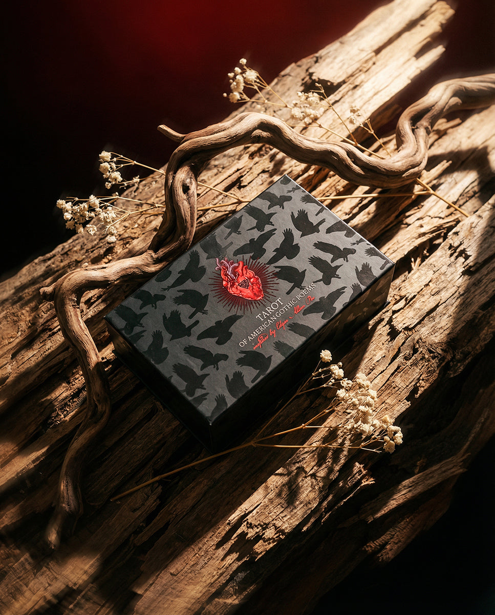 Card with a red and black design on a wooden surface with dried plants