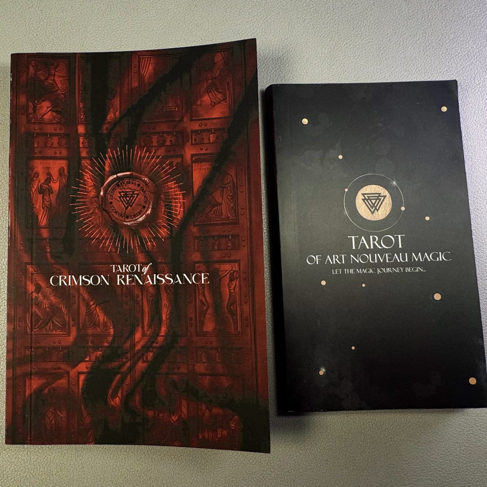 Three tarot card books on a gray surface